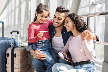 Happy Arab Parents With Cute Little Daughter Waiting For Flight In Airport