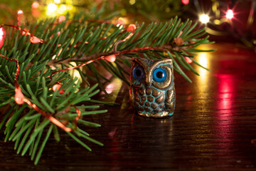 Metal souvenir owl next to a spruce branch with Christmas lights. Christmas New Year or composition