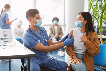Vaccinated Asian Lady Gesturing Thumbs Up At Clinic