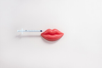 Medical syringe and red toy lips. Lip injection creative concept. Selective focus, copy space