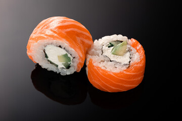 sushi rolls with white rice, red fish, philadelphia cheese, avocado, salmon, nori 2 pieces on a black background