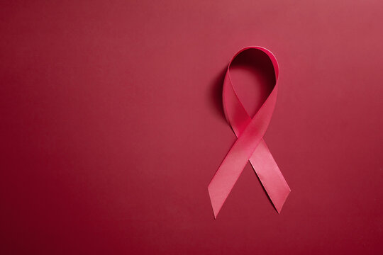 Red ribbon symbol of world aids day on red background copy space