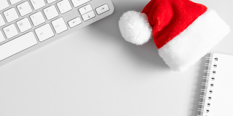 Christmas or New Year background. Office table, santa hat, christmas decorations, keyboard on gray...