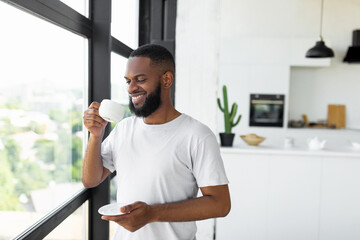 Smiling African American man drinking coffee near window
