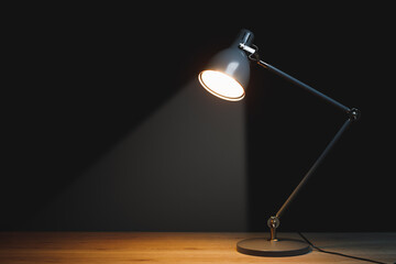 Fototapeta na wymiar desk lamp with spotlight, black background with copy-space