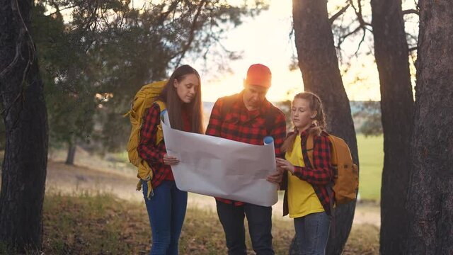 group of tourists hiker with a map. happy family with backpacks travel. adventure kid dream concept. happy family hiker in forest park with backpacks looking for path on lifestyle paper map