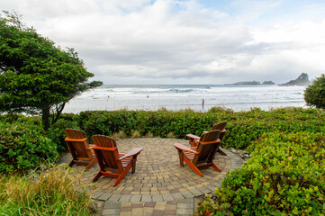 Tofino Vancouver Island Canada. Adirondack chairs facing the beach of Cox Bay on a sunny day. People are walking on the beach