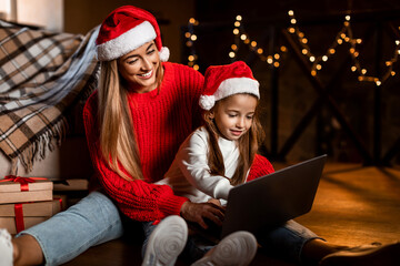 Portrait of happy festive woman and daughter using laptop