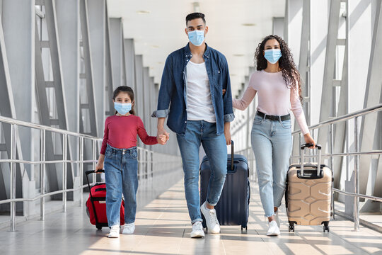 Pandemic Travels. Arab Family Of Three Wearing Protective Masks Walking At Airport