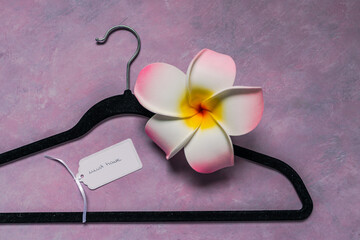fashion industry and shopping trends, velvet clothes hanger on pink background with Must Have label and decorative flower