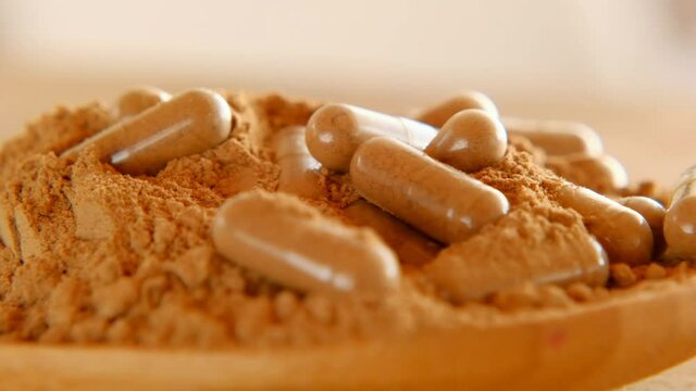 Guarana capsules in guarana powder in a wooden spoon. Healthy eating. 4k footage