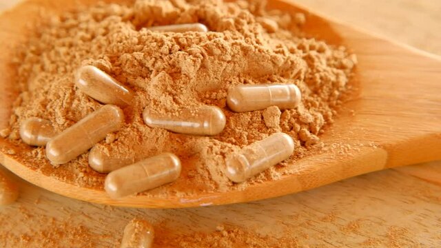 capsules with guarana powder.Guarana capsules in guarana powder in a wooden spoon on a wooden table. Natural tonic.Supplements and vitamins. Healthy eating. sports nutrition. 4k footage