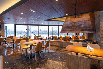 Interior of an empty mountain restaurant with large fireplace in the middle