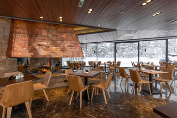Interior of an empty mountain restaurant with large fireplace in the middle