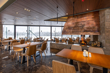 Interior of an empty mountain restaurant with large fireplace in the middle
