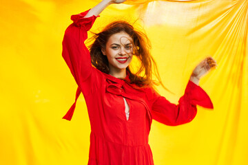 cheerful woman in red dress posing in nature yellow cloth