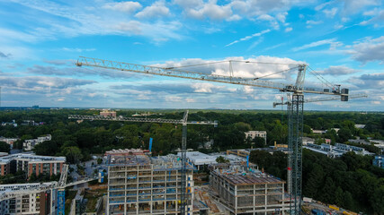 a majestic shot of talk tower cranes at a construction site surrounded by buildings in the...
