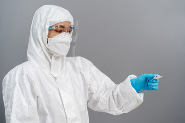 doctor in PPE suit looking temperature at digital thermometer