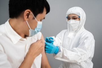 doctor in PPE suit syringe and using cotton before make injection to patient in medical mask. Covid-19 or coronavirus vaccine