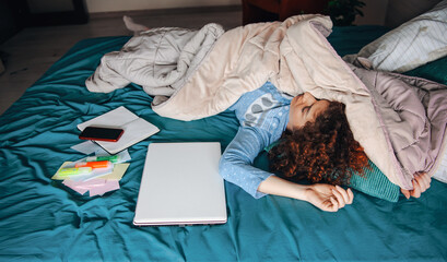 Portrait of a woman sleeping in bed while sitting next to her latest generation of technology laptop phone different notebooks