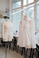 Obraz premium White handmade sewing shirt on dummy at studio sew workshop. Fashion dressmaker or seamstress