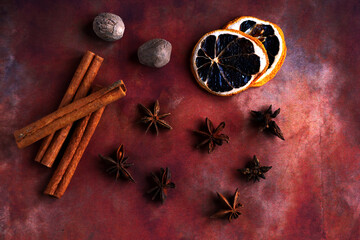 Ingredients for cooking winter drinks such as mulled wine. Cinnamon sticks, nutmeg, star anise, dehydrated lemon slices on brown background. Top view