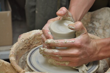 the potter's hands create a vase of clay on a potter's wheel