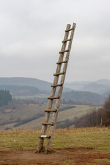 Old wooden ladder on the meadow leading high up in the sky . Ladder to heaven. Symbol of career.