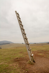 Fototapeta na wymiar Old wooden ladder on the meadow leading high up in the sky . Ladder to heaven. Symbol of career.