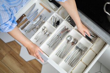 Top view closeup housewife hands tidying up cutlery in drawer general cleaning at kitchen - obrazy, fototapety, plakaty