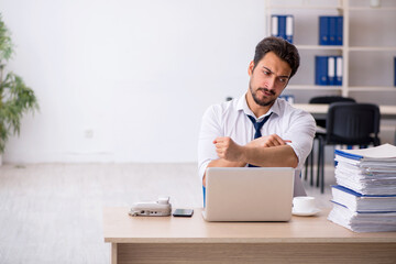 Young male employee unhappy with excessive work in the office