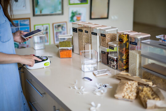 Woman professional space organizer creating stickers with names of bulk products use labeler machine