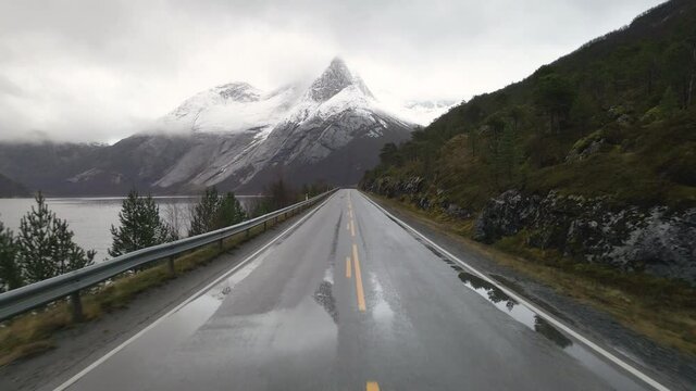 Wet Arctic road in direction of snow-covered Stetind mountain, Tysfjord, Norway