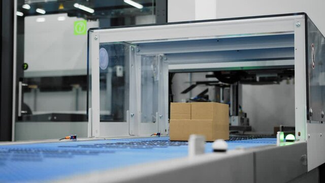 Boxes on conveyor belt fed into machine where labels are attached; mechanization
