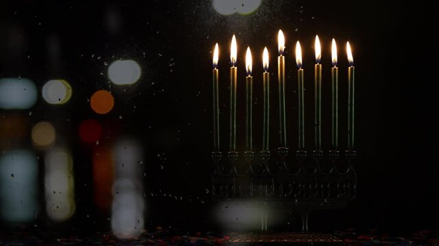 Burning menorah with golden candles and confetti defocused light background. Jewish holiday Hanukkah symbol.