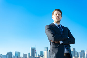 青空とビル群を背景にしたビジネスマンのポートレート