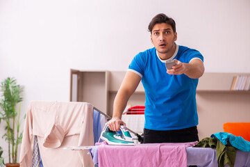 Young man husband doing ironing at home