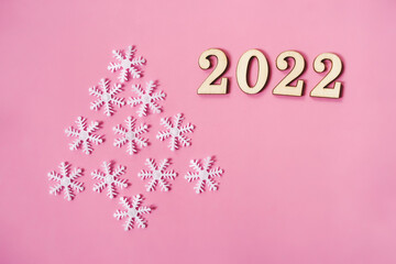 Fototapeta na wymiar Pink pastel flatlay with snowflakes and wooden eco-friendly Christmas and New Year 2022 decorations