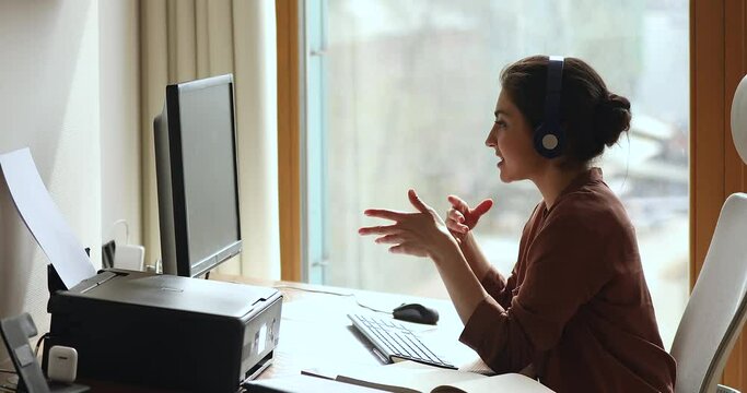 Confident Indian business lady freelancer working from home meet customer online speak to client by video call. Young female remote worker in headset present idea to teammates on remote web conference