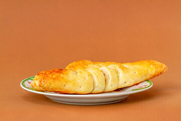 A croissant on a small plate for breakfast and coffee, brown background