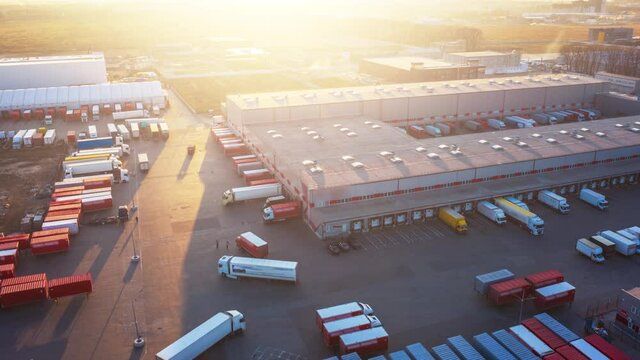 Hyper lapse (hyperlapse - motion time lapse) of a logistics park with a loading hub. Semi-trailer trucks standing at warehouse ramps for loading and unloading goods. Aerial panoramic view