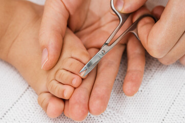 Baby nail cut. Hand with scissors trims toenails of a sleeping baby. Selective focus