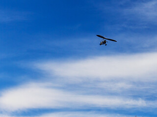 Flying a motorized hang glider on an autumn sunny day.