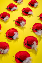 Fifteen felted wool hats with a feather on a yellow background