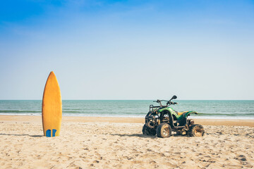 Fototapeta na wymiar Vintage green ATV on the sandy beach. Quad ATV all terrain vehicle parked on beach, Motor bikes ready for action with summer sun flaring on bright day. Outdoor extreme activity adrenaline sport.