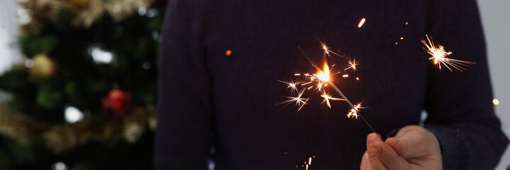 Man holds lighted sparkler in dark closeup