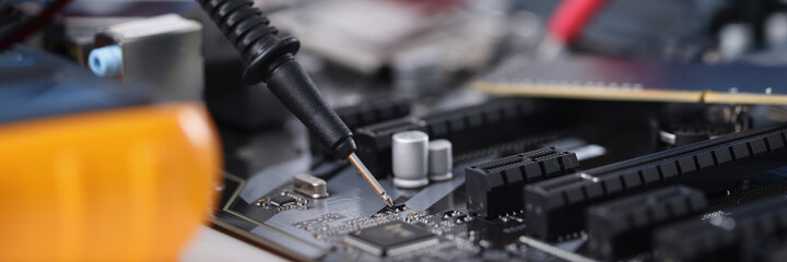 Master in gloves with equipment is testing computer motherboard