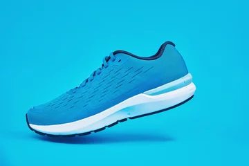 Foto op Plexiglas Blue running sneaker close up. Sport male shoe steps on blue background. Fitness concept © Lazy_Bear