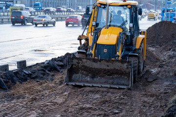 Yellow excavator, bulldozer and working tractor. Road works in the city center. Road equipment on the construction site, civil engineering, construction of a new sidewalk in the city