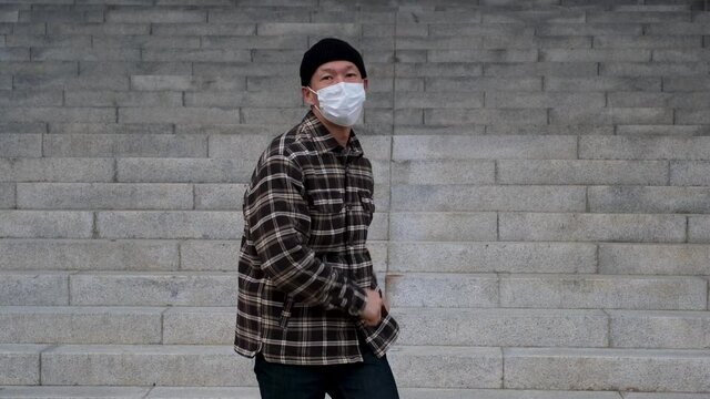 Asian man in medical mask dancing on background of concrete stairs close-up.